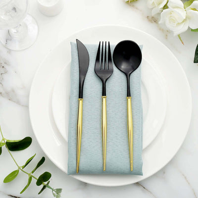 Black cutlery set with gold handles on a blue napkin atop a white plate.