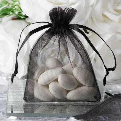 Black organza bag filled with white candy almonds.