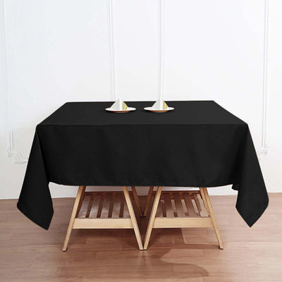 Black tablecloth draped over a wooden table with candle holders on top.