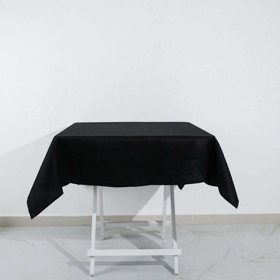Black tablecloth draped over a white folding table