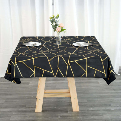 Black geometric tablecloth with gold accents on a wooden table setting.