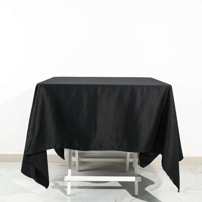 Black tablecloth draped over a white table on a plain background