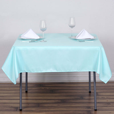 Mint green tablecloth on a dining table set with glasses and napkins.