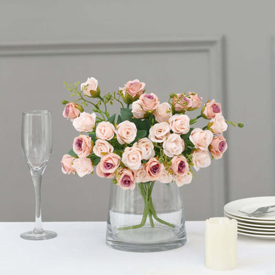 Floral arrangement of pink and lavender roses in a glass vase.