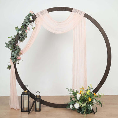 Decorative wedding arch with drapery, flowers, and lanterns.