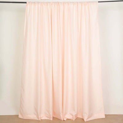 Peach-colored curtain draped on a rod against a plain background