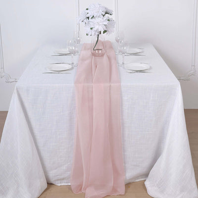 Elegant table setting with pink runner, white plates, and floral centerpiece.