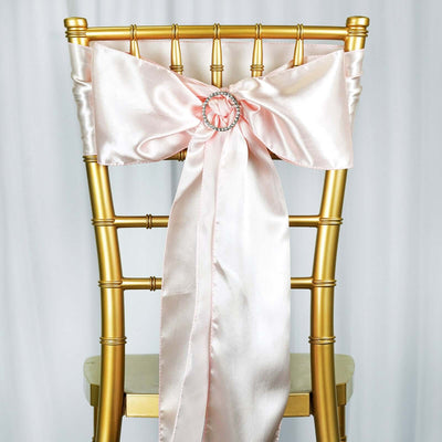 Pink satin chair sash with a decorative rhinestone buckle on a gold chiavari chair.