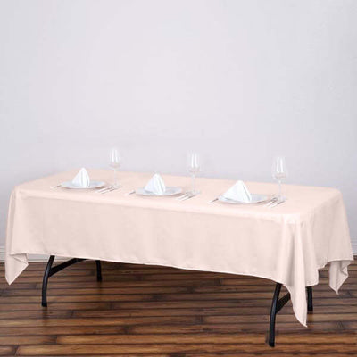 Beige tablecloth draped on a table set for dining with glassware and napkins.