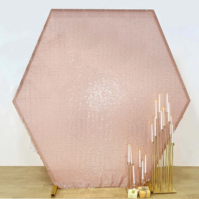 Rose gold hexagon backdrop with elegant gold candle holders and candles.