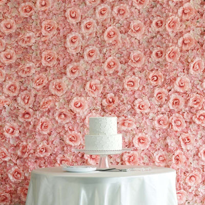 Elegant white wedding cake on a pedestal with a pink floral backdrop.