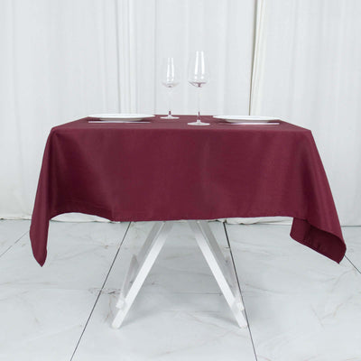 Elegant burgundy tablecloth draped over a white table with wine glasses and plates.