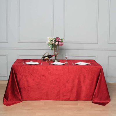 Elegant red tablecloth draped on a table set with plates and flowers.