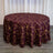 Round burgundy tablecloth with gold geometric pattern on a wooden surface.
