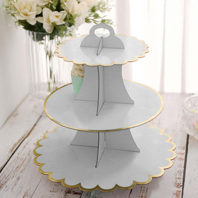Three-tiered white dessert stand with scalloped edges and gold trim.