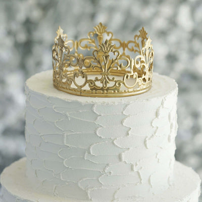 Elegant gold crown atop a textured white cake against a blurred background.