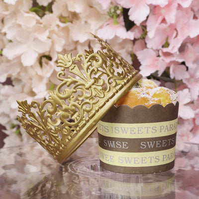 Gold crown resting on a cupcake with floral background.