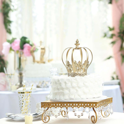 Elegant white cake with a gold crown topper on a decorative stand.