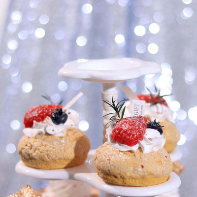 Dessert cupcakes topped with strawberries and cream on a tiered stand.