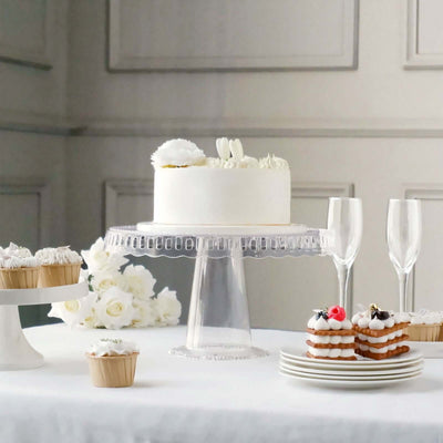 Elegant white cake with cupcakes and pastries on a table setting.