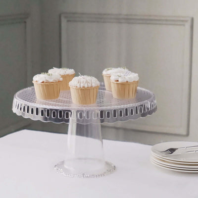 Clear cake stand with five decorated cupcakes on a table.