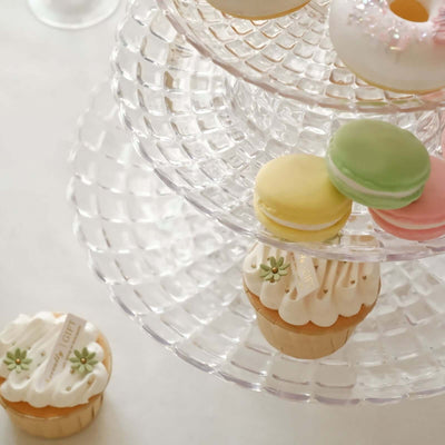 Colorful macarons and cupcakes on a tiered dessert stand.