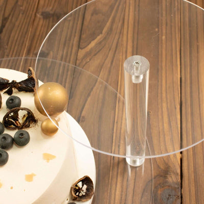 Acrylic cake stand with decorative elements on a wooden surface.