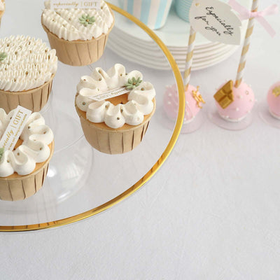 Decorative cupcakes on a glass stand with sweet toppings and gift tags.