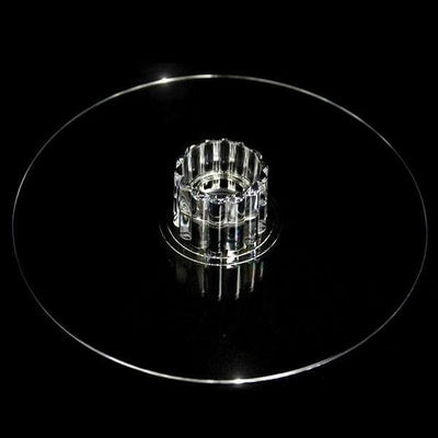 Clear glass cake stand with decorative base, isolated on black background.