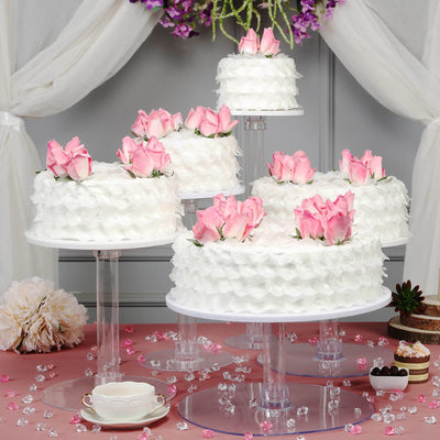 Beautifully decorated white cakes with pink roses, elegantly displayed on clear stands.