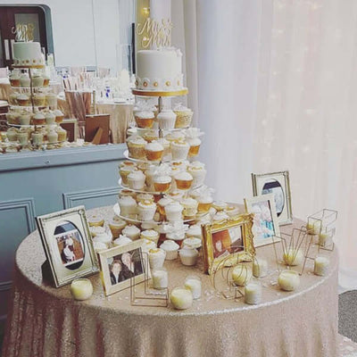 Elegant cupcake display with wedding decorations and framed photos.