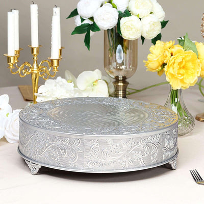 Decorative silver cake stand with intricate floral design on a table setting.