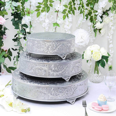 Decorative silver cake stands in three tiers with floral backdrop.