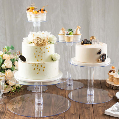 Elegant display of three tiered cakes with decorative cupcakes on clear stands.