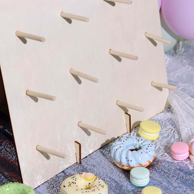 Wooden display board with pegs, showcasing colorful donuts and macarons.