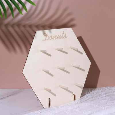 Wooden donut display stand on a pink background.