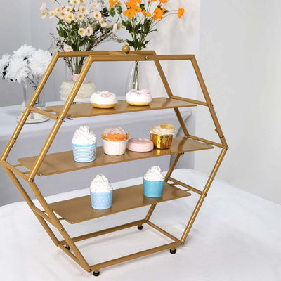 Gold hexagonal dessert stand with colorful cupcakes and flowers in the background.