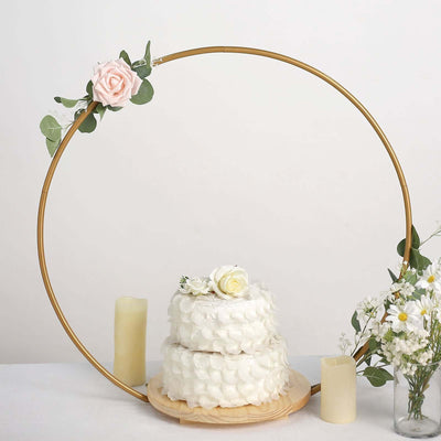 Two-tiered wedding cake decorated with flowers, set against a minimalist backdrop.