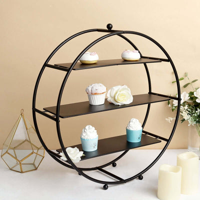 Black circular cupcake stand with three shelves and decorative cupcakes.