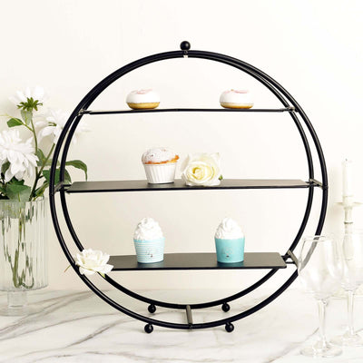 Elegant black metal display stand with cupcakes and flowers on a marble surface.