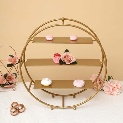 Gold three-tier dessert stand with pastries and flowers, styled on a soft background.