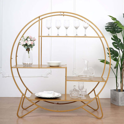 Gold circular shelf with glasses, plates, and decor, against a white backdrop.
