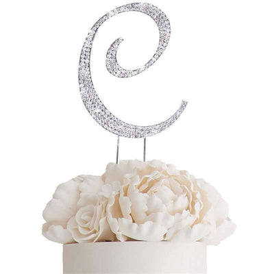 Silver glitter letter "C" cake topper on white flower arrangement.