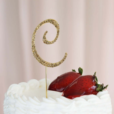 Gold glitter cake topper in a swirl design with strawberries on a white cake.