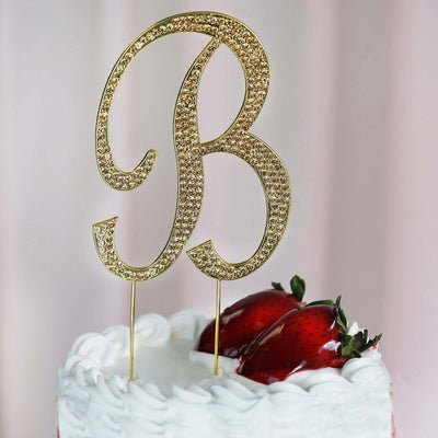 Gold glitter cake topper letter "B" on a cake with strawberries.