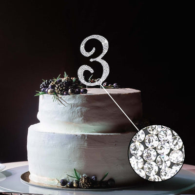 Sparkling number 3 cake topper on a decorated cake.