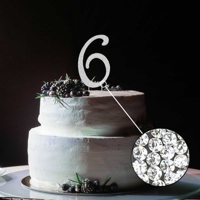 Silver glitter number 6 cake topper on a white frosted cake with berries.