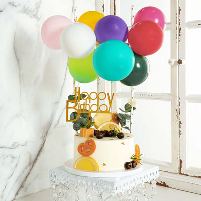 Birthday cake decorated with colorful balloons and fruit accents.