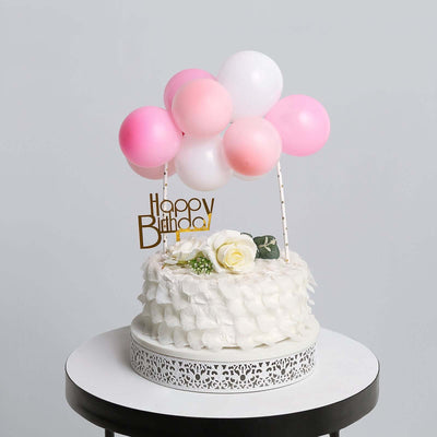 Birthday cake with balloons and decoration on a round table.