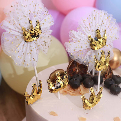 Gold crown cake toppers with tulle and sequins for celebration decor.